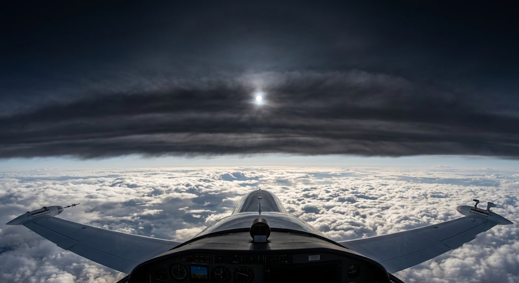 High-altitude view above the clouds showing a dense dark haze of soot spreading through the stratosphere and blocking the sun.